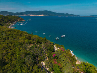 Naklejka na ściany i meble Boats anchored off forested headland along coastal bay in Nha Trang Vietnam