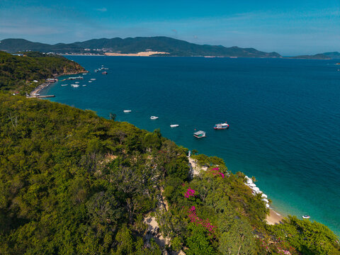 Boats anchored off forested headland along coastal bay in Nha Trang Vietnam