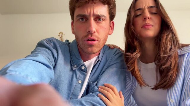Worried young couple looking down with confused and surprised expressions, trying to understand or fix something out of frame, seen from a low angle point of view inside a home