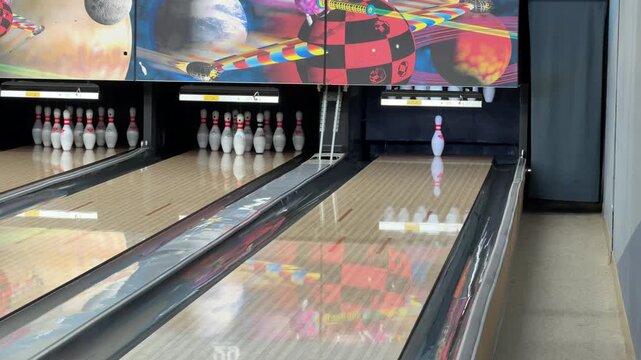 Person hitting the last standing center pin with a bowling ball during an exciting indoor bowling game at the alley.