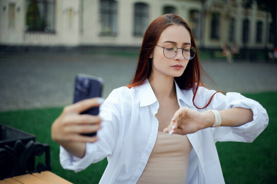 Businesswoman engaged in video call while checking time outdoors in city setting