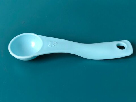 Top view of blue plastic measuring spoon 5ml 5g on blue background