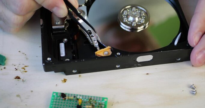 Hands repair hard drive components. Precision tools work on internal mechanisms. Technological maintenance ensures data integrity. Essential process for data recovery and protection.