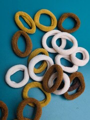 Fototapeta premium Top view of assorted seamless fabric hair ties in brown, white, and yellow on blue background