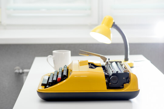 Writer desk with yellow vintage typewriter and coffee cup