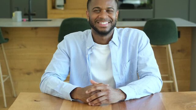 Handsome young african american male professional gesturing and speaking during a job interview or a video conference call, expressing confidence and positivity from a modern office space