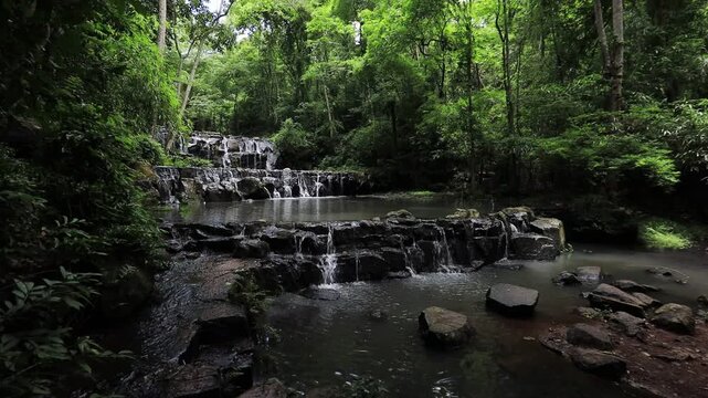 The video background features a natural landscape of a waterfall in a lush forest. Sam Lan Waterfall in Saraburi National Park boasts beautiful flowing water surrounded by diverse flora.