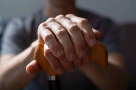 Middle age caucasian man hands holds cane closeup