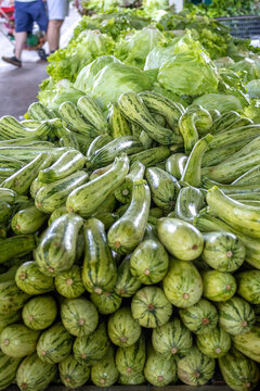 Fresh Organic Zucchini Pile at Farmers Market - Abundant Green Summer Squash and Lettuce Background for Healthy Eating, Farm to Table Cooking, and Sustainable Living