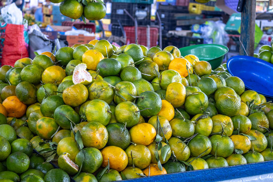 Fresh Green and Orange Tangerines at Outdoor Farmers Market with Peeled Citrus Fruit