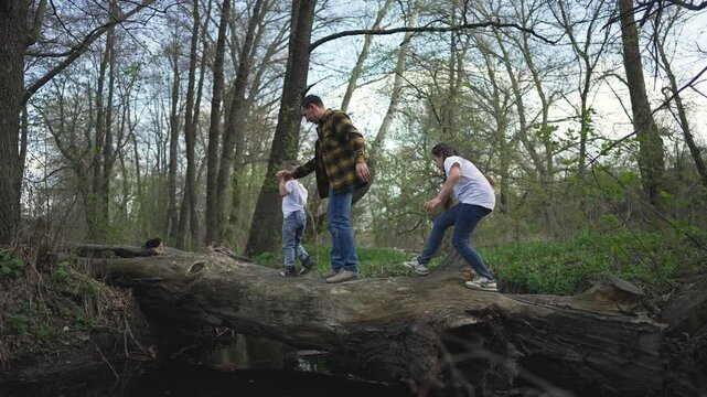 Children navigate log outside adventurous outdoor play. Kids balance on fallen log wild forest exploring nature. Active children enjoy exploring outside teamwork natural log. outdoor travel concept.