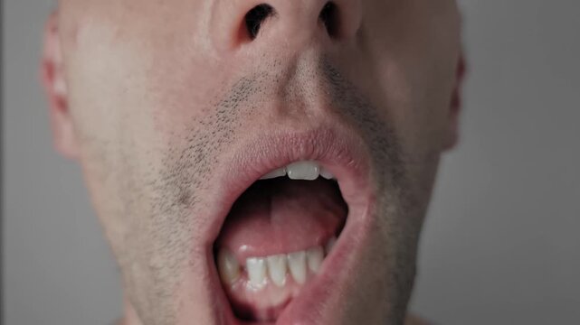 A male pulls down his lower lip to expose teeth and gums for inspection in a detailed macro view. The visual illustrates routine dental checkups, oral hygiene, and gum health awareness.