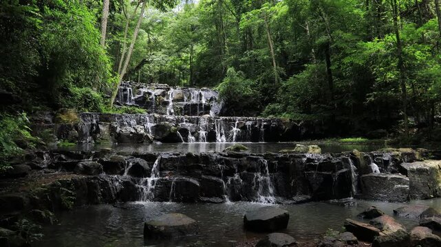The video background features a natural landscape of a waterfall in a lush forest. Sam Lan Waterfall in Saraburi National Park boasts beautiful flowing water surrounded by diverse flora.