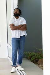 Naklejka premium African American man leaning in doorway by sliding door wearing striped shirt jeans sneakers