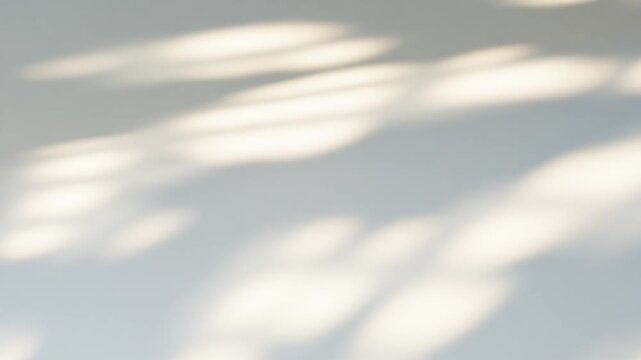Sunlight casting a blurred window shadow moving on a neutral white wall creating a seamless loop background