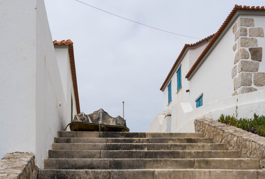 Steps and a boat with white and painted houses by the coast
