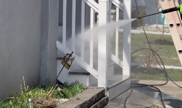 Power washing stairs leading to house with nozzle