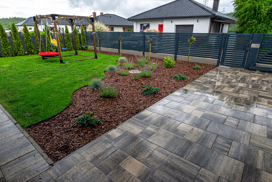 Wet backyard garden with paved driveway and swing set
