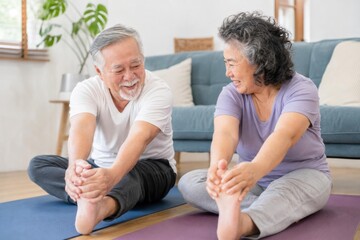Fototapeta premium Happy elderly couple stretching together in a cozy indoor setting, promoting fitness and wellness in later life.