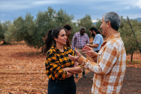 Farmers conversing in olive grove during agriculture community meeting