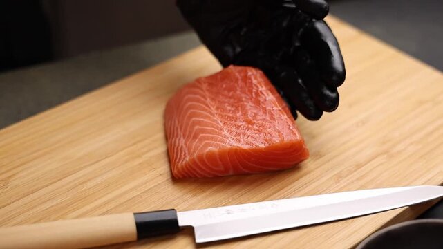 Close-up of a chef slicing fresh salmon on a wooden cutting board. Sharp knife, detailed texture of raw fish, and professional kitchen atmosphere emphasize precision, freshness, and gourmet culinary p