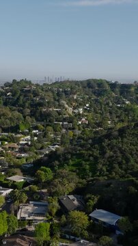 Backwards reveal of houses in hills above metropolis. Revealing downtown skyscrapers in distance. Los Angeles, California, USA