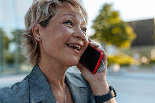 Happy businesswoman talking smartphone outdoors
