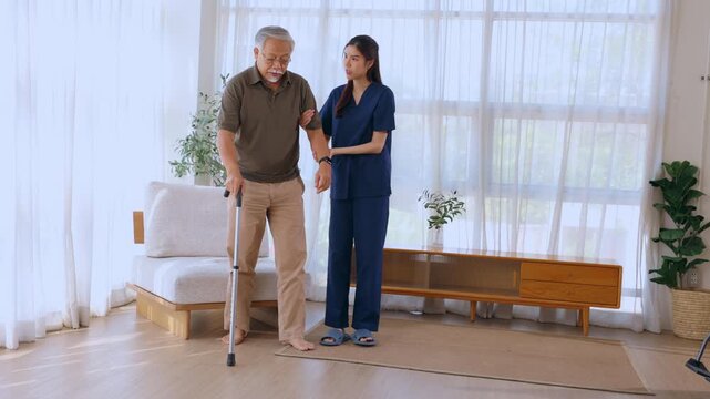 Senior man caregiver walking cane home care assistance recovery support living room mobility aid balance health aide helping elderly male stand calmly