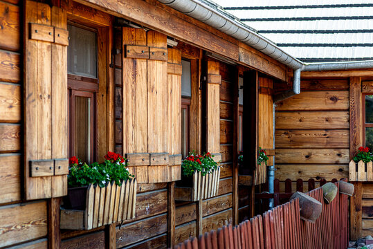Rustic wooden house facade with traditional shutters and geraniums