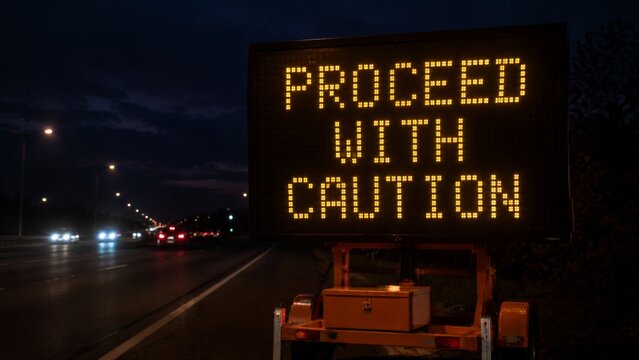 A mobile highway sign at night warning motorists to proceed with caution