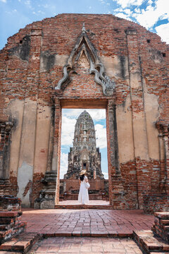 Framed view of the ancient central prang of Wat Ratchaburana through a historic brick doorway with a female tourist, Ayutthaya, Thailand