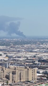 Urban expanse of Los Angeles showing LAC plus USC Medical Center with large column of black smoke rising from a building fire, polluting cityscape