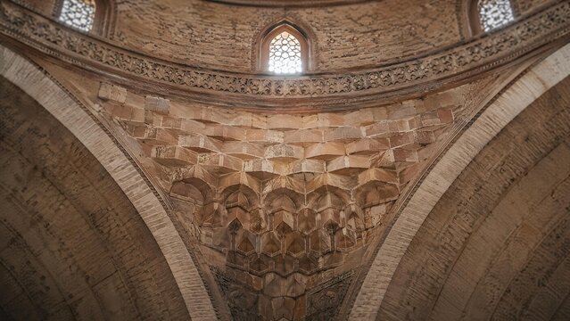 A stone squinch arch supporting a dome inside an ancient mosque.