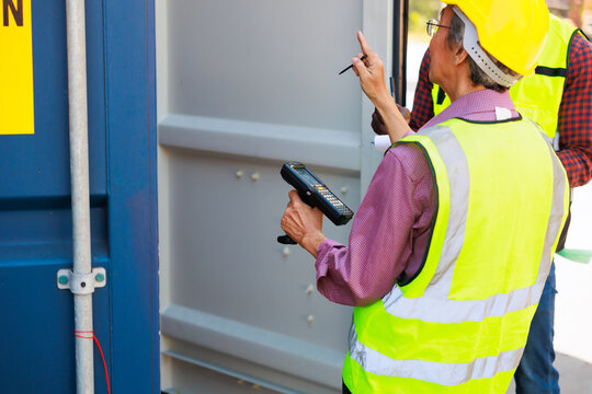 Old man warehouse worker and black male dock worker use barcode scanner at warehouse container yard
