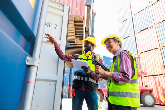 Old man warehouse worker and black male dock worker use barcode scanner at warehouse container yard