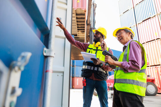 Old man warehouse worker and black male dock worker use barcode scanner at warehouse container yard