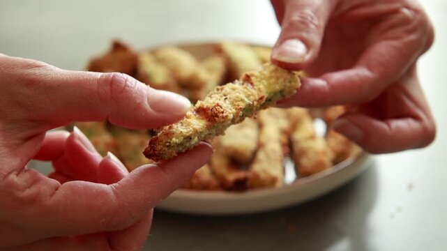 Close-up of golden, crispy baked zucchini fries stacked neatly on a ceramic plate, served with a healthy dipping sauce