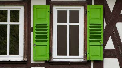 Fototapeta premium traditional half timbered house facade with window and bright green shutters