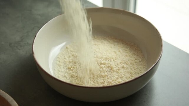 mixing crunchy panko breadcrumbs, grated parmesan cheese, and savory spices in a glass bowl to create a crispy breading mixture