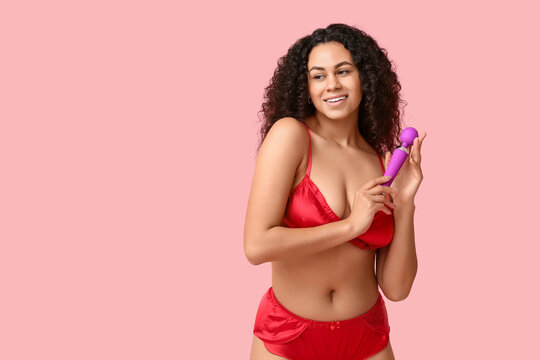 Smiling young woman in red lingerie holding purple vibrator, female pleasure and intimacy concept, self-care and wellness