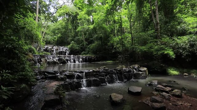 The video background features a natural landscape of a waterfall in a lush forest. Sam Lan Waterfall in Saraburi National Park boasts beautiful flowing water surrounded by diverse flora.