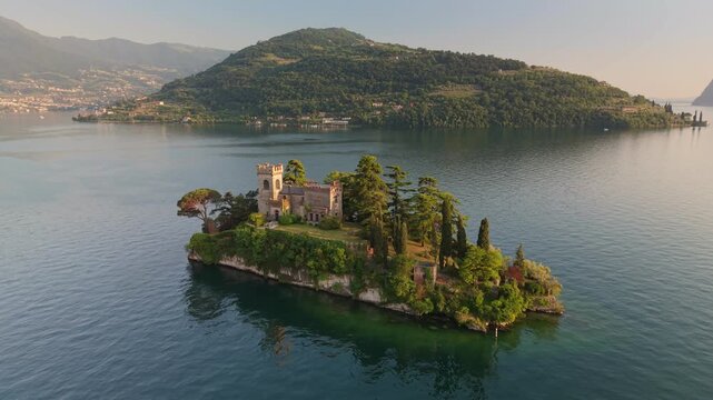 Aerial view of Isola di Loreto with its neo gothic castle, isolated island on Lake Iseo in Italy. Isola di Loreto private island with ancient fortress and cypress trees, Lombardy region
