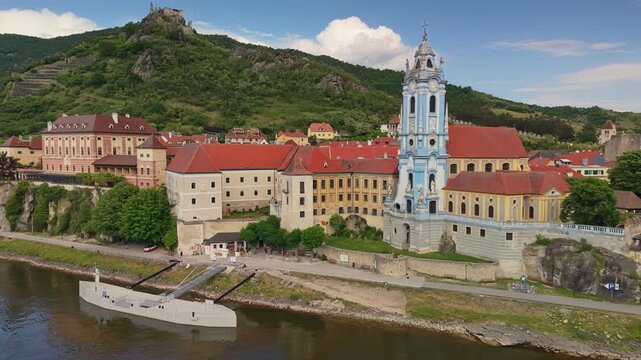 Aerial view of famous blue church tower of Durnstein abbey, historic town on Danube river shore in Austria. Durnstein village with monastery and medieval castle ruins, Wachau valley in Austria