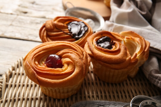 Tasty cruffins with jam and chocolate on white wooden background