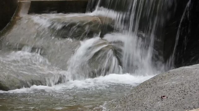 Video A small man-made waterfall or weir cascading clear water over smooth rocks into a splashing pool below