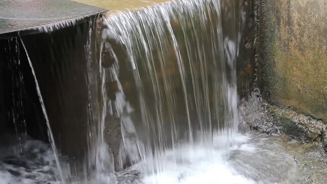 Video A small man-made waterfall or weir cascading clear water over smooth rocks into a splashing pool below
