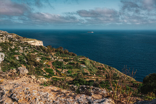 landscape of the dingli cliffs from the coast with limestone cliff face, lush green foliage on summer evening sunset with Mediterranean Sea below on overcast day