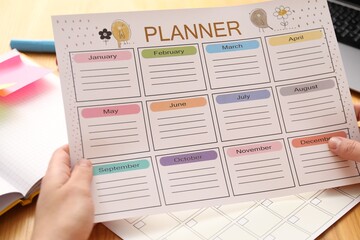 Obraz premium Woman using planner at wooden table, closeup