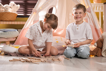 Little girl and boy playing with building blocks in wigwam at home © New Africa