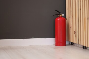 Obraz premium One red fire extinguisher on floor indoors, space for text